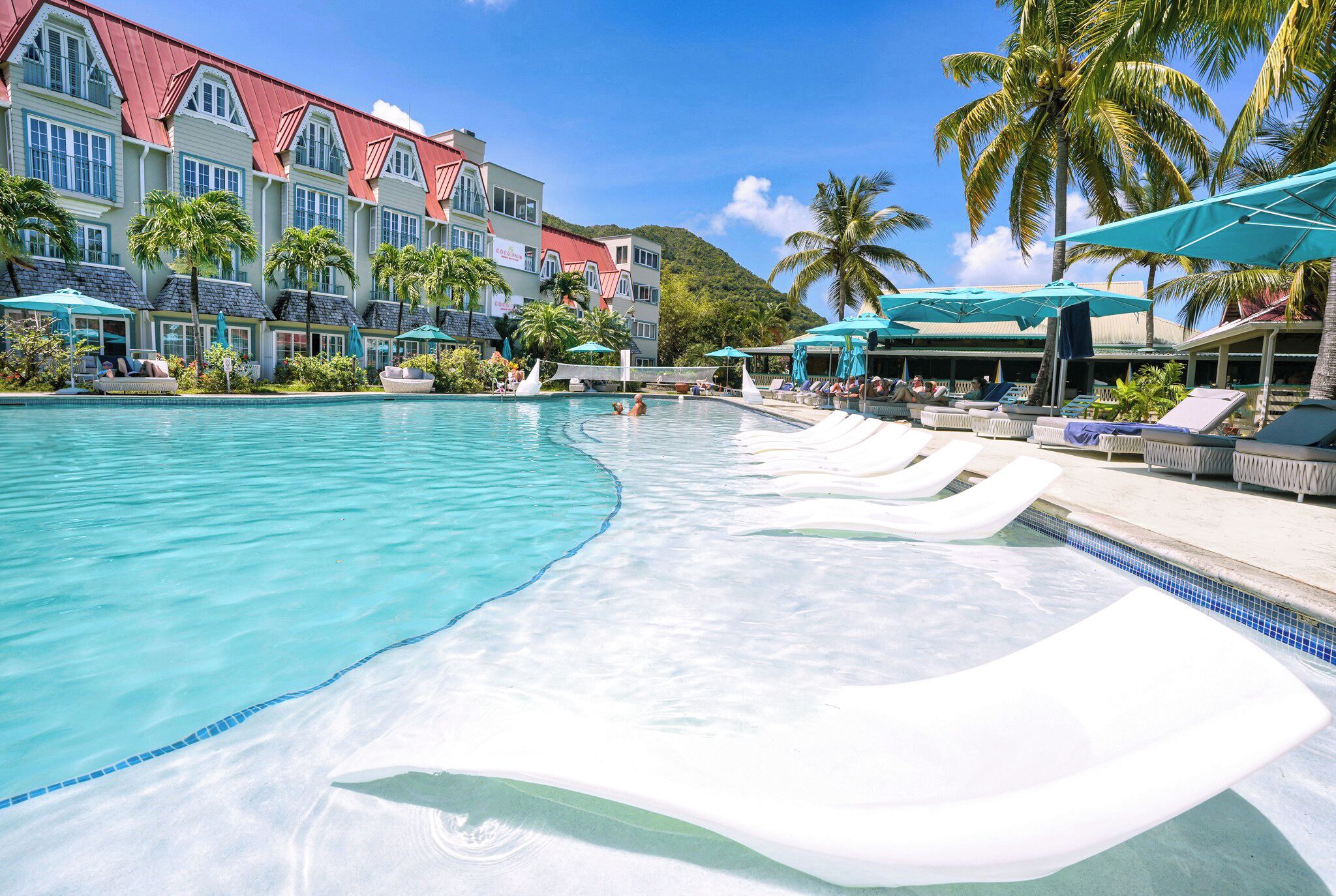Una piscina al aire libre, sombrillas, sillones reclinables de piscina