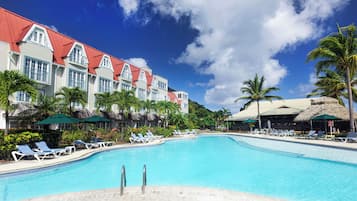 Relax by the resort's pool surrounded by lounge chairs and umbrellas under the shade of palm trees.
