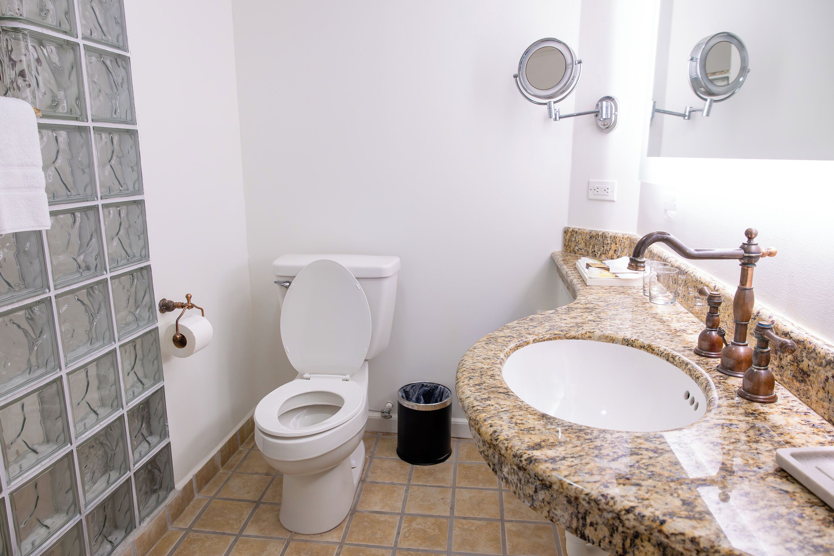 A bathroom with a toilet, sink, and two wall-mounted mirrors.