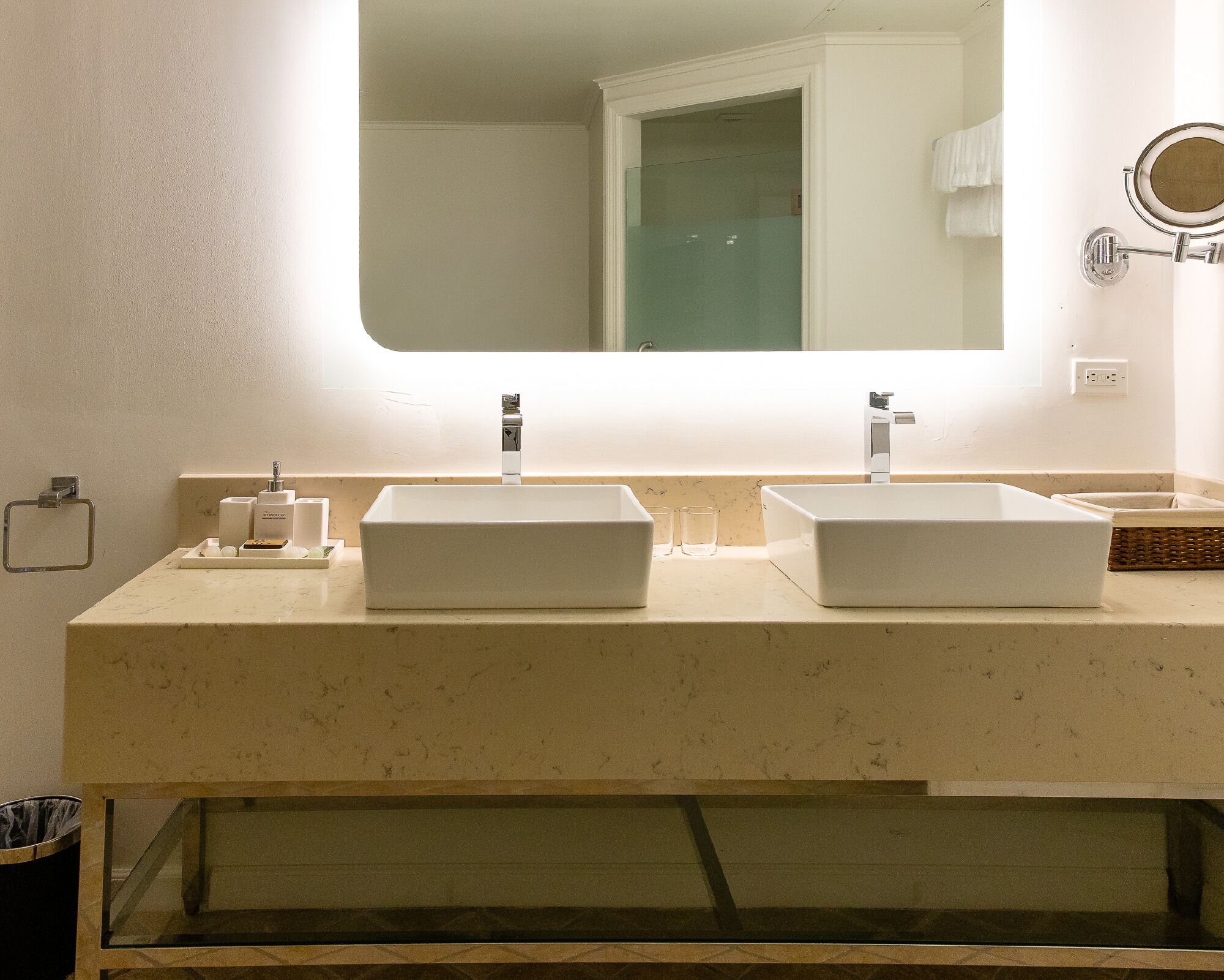 A bathroom with a double sink, a mirror above the sink, and a towel rack to the right.