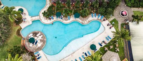 Una gran piscina con varias terrazas, rodeada de palmeras y tumbonas.