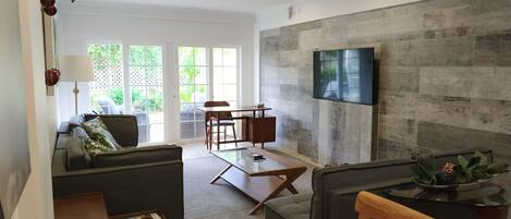 Una sala moderna con sofá, mesa de centro y televisión instalada en la pared.