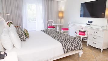 A hotel room with a large bed, a desk, a chair, a TV, and a window with curtains.