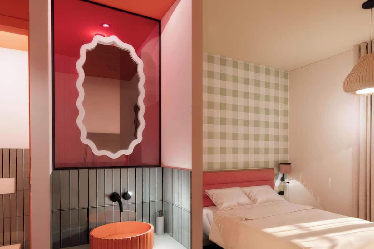A modern bedroom with a checkered wall, a round orange sink, a bed with white bedding, and a pendant light.