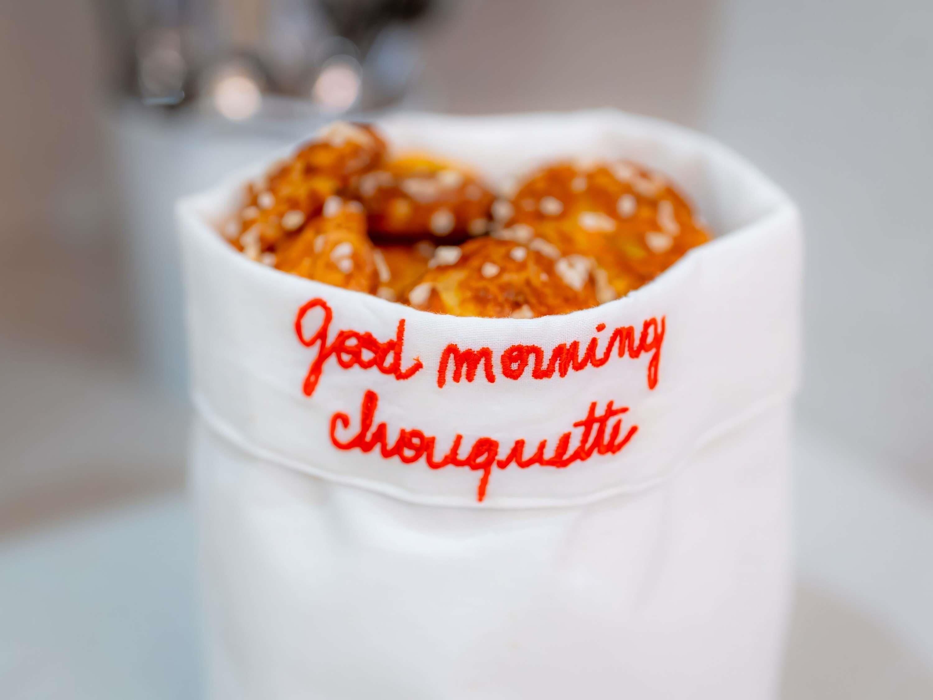 A white mug with the text 'Good morning chouette' and a close-up of a pretzel.