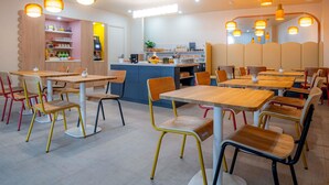 A modern dining area with wooden tables and chairs, a central counter, and pendant lighting.