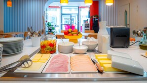 Montaje de bufé con diversos alimentos, utensilios y una máquina de café.