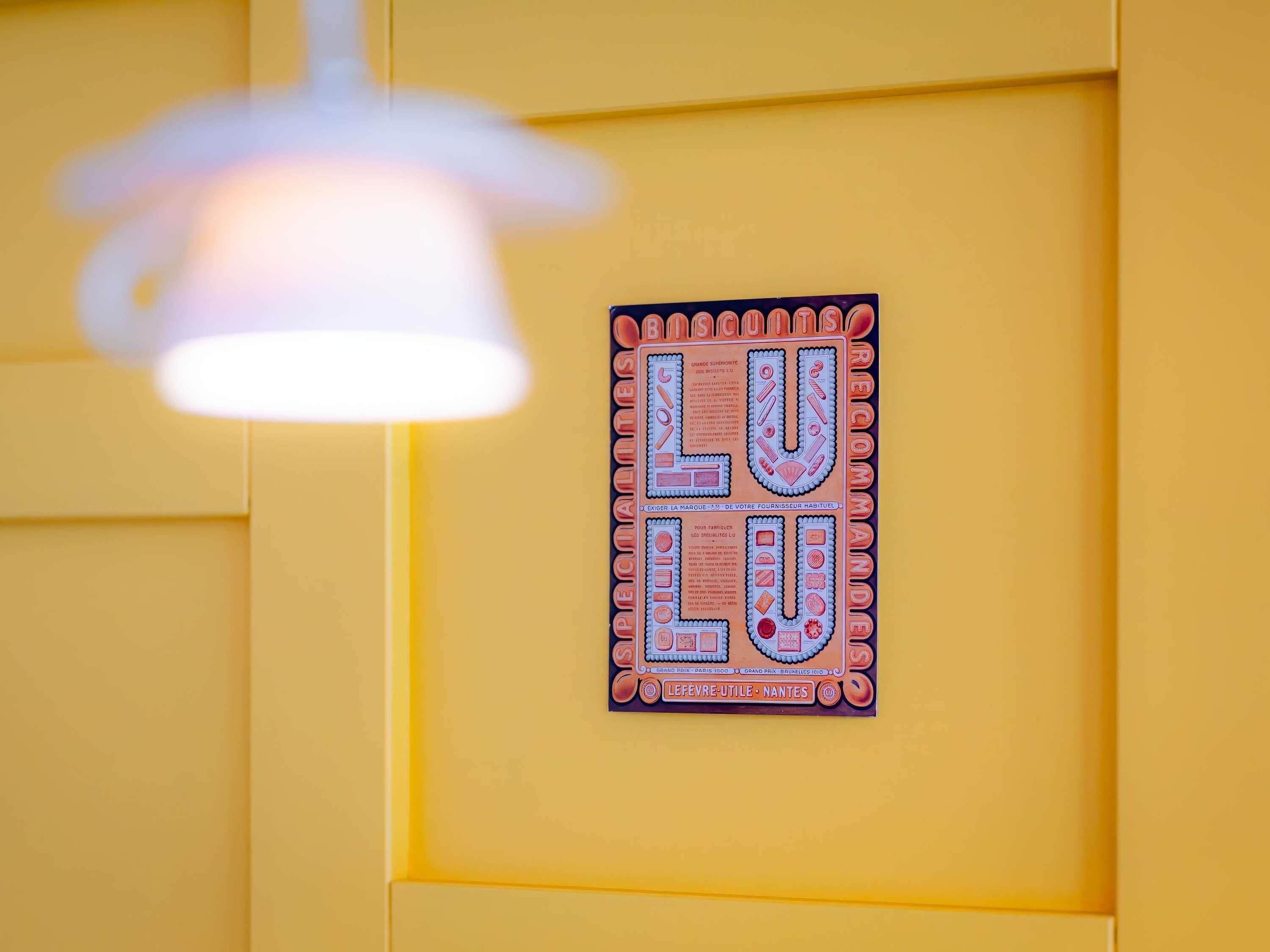 Una pared amarilla con un letrero que dice 'LULU' y 'RECOMENDADO' en una tipografía decorativa.