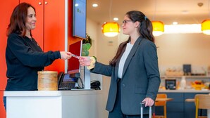 A reception desk with a digital screen, a telephone, and a small plant.