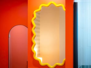 A mirror with a wavy yellow frame on an orange wall. - ibis Styles Nantes Centre Place Graslin (Nantes)