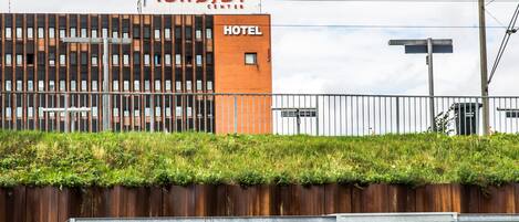 A hotel with a modern design, a visible sign for the Ishøjby Hotel, and a bike parking area.