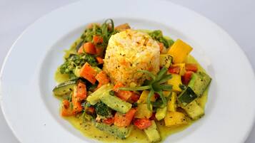 A plate of food with a mound of rice, various vegetables, and a garnish.