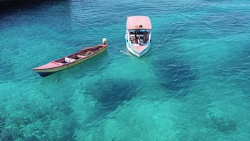 Dos barcos sobre aguas turquesas y transparentes.
