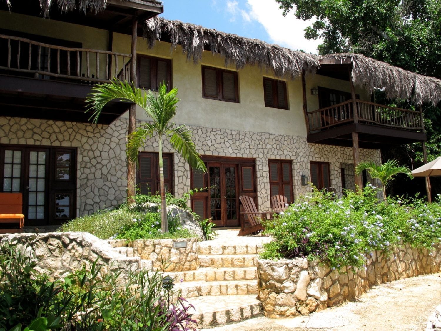 A two-story building with a stone facade, wooden balconies, and a thatched roof.