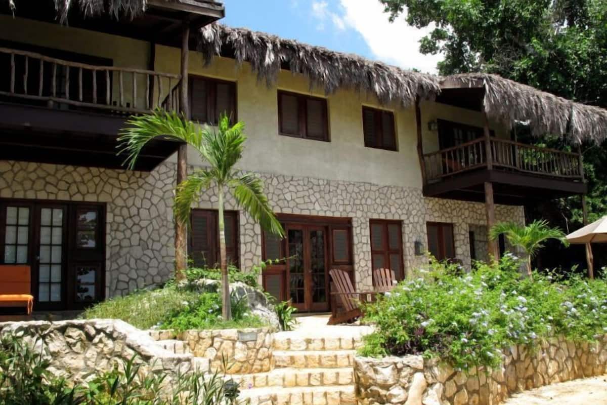 Un edificio de dos pisos con fachada de piedra y balcones de techo de paja.