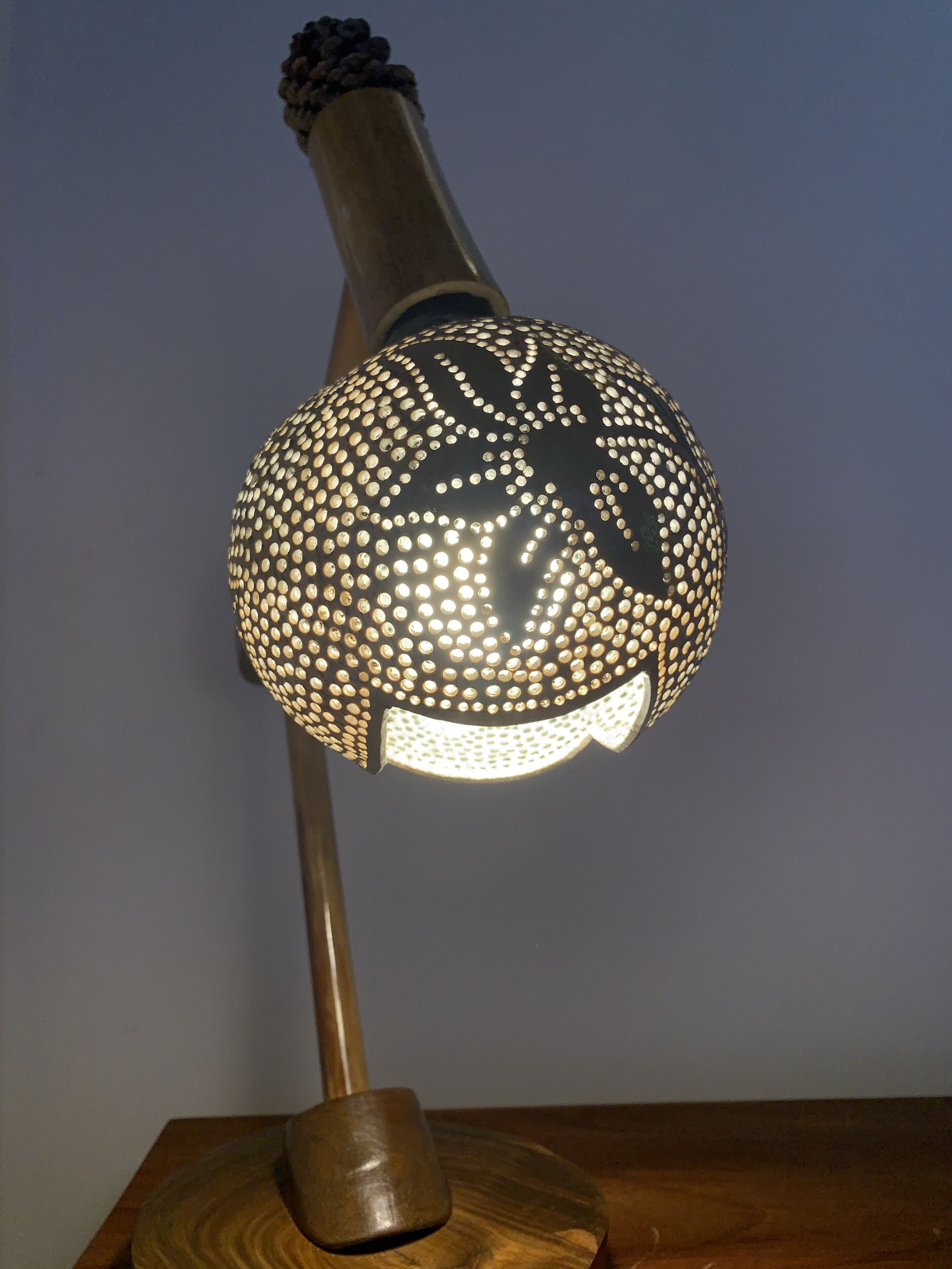 Una lámpara con pantalla esférica y base de madera.