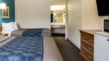 A hotel room with two beds, a dresser, a television, and a mirror.