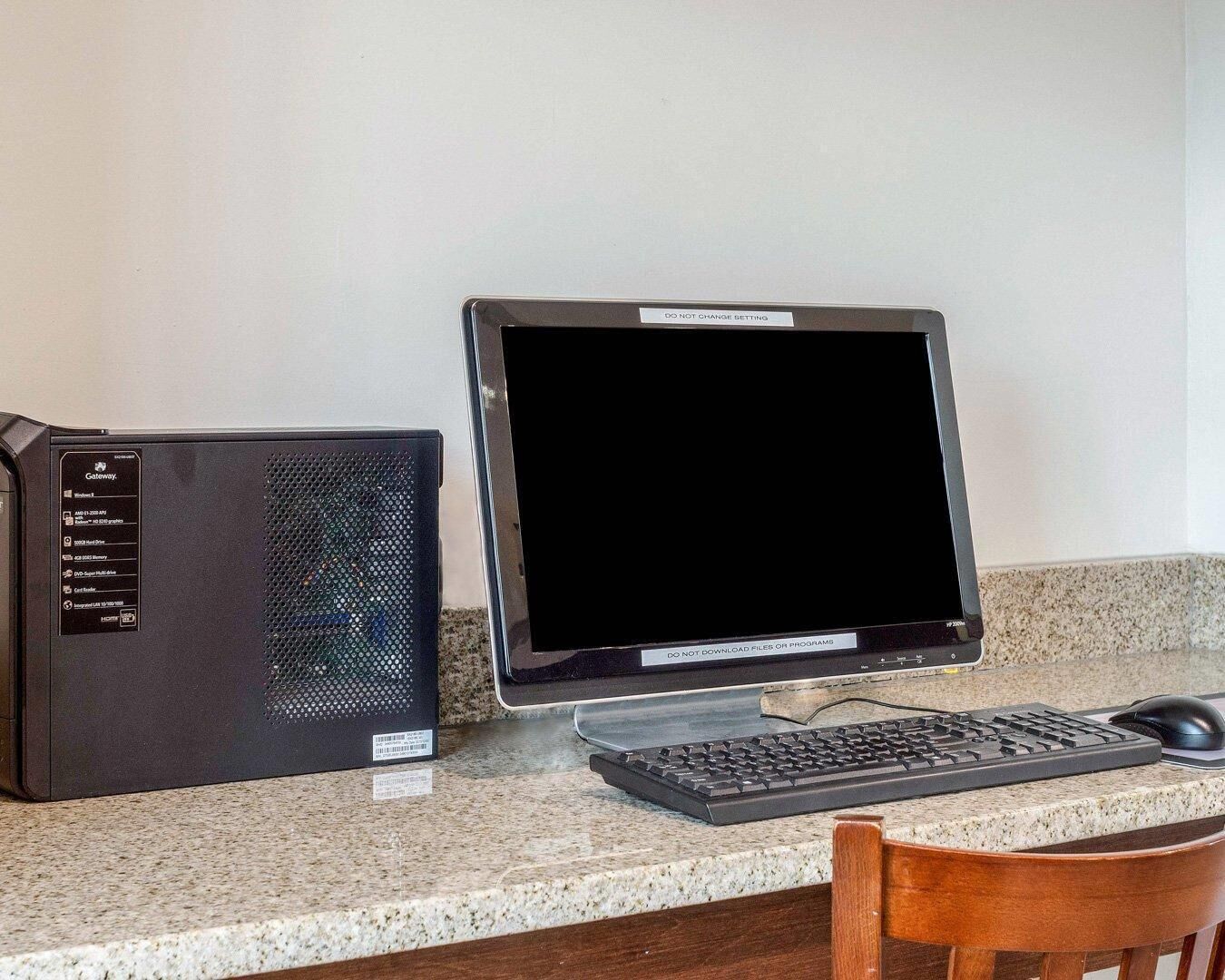 A desktop computer with a monitor, keyboard, and mouse on a granite countertop.