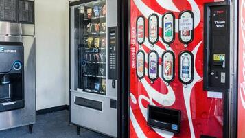 A vending machine with a red and white design, a water dispenser, and a soda machine.