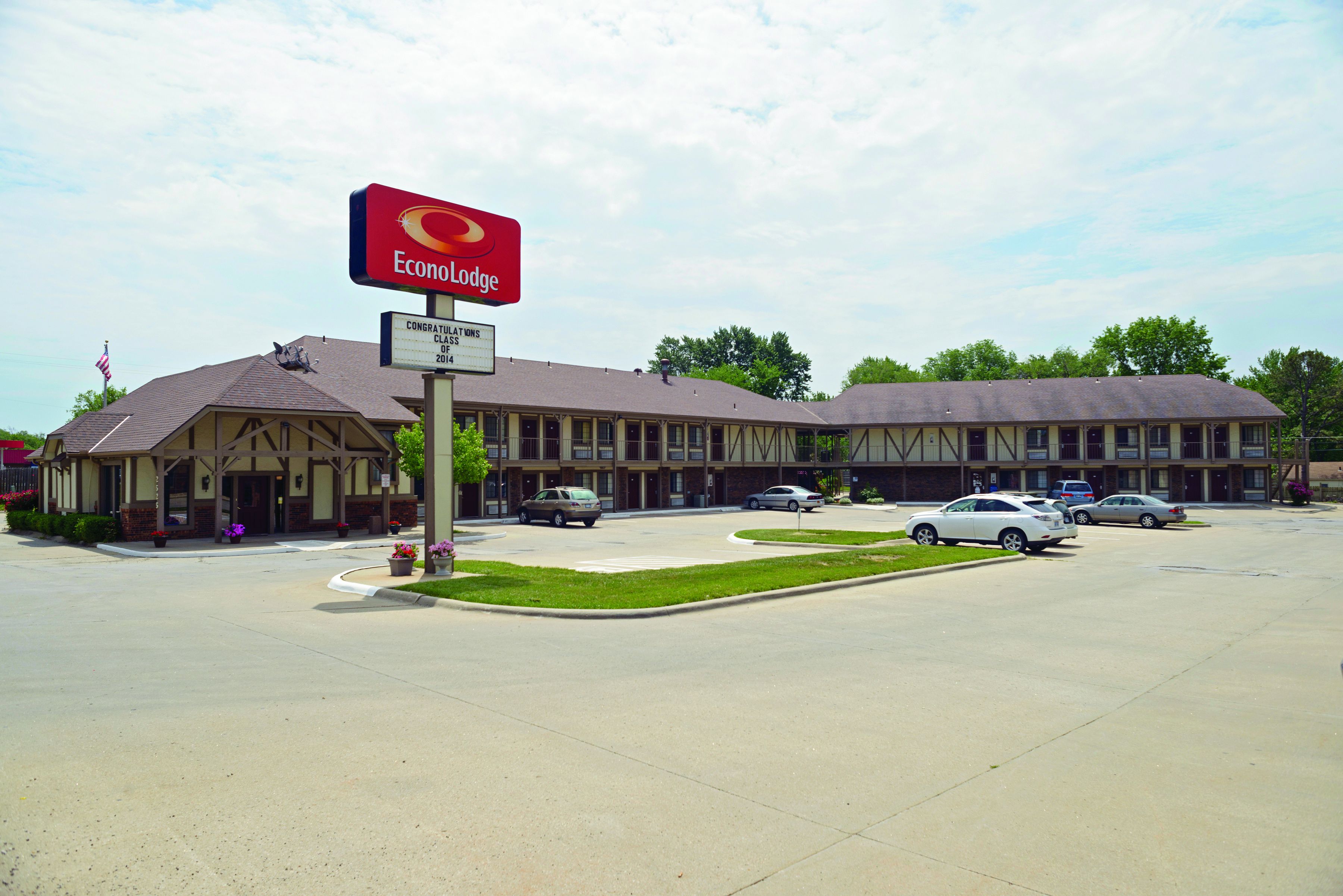 A motel with a large sign for Econolodge, a parking lot with several cars, and a building with a traditional architectural style.