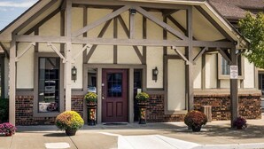 A building with a gabled roof, a central entrance with a door, and a sign indicating reserved parking. - Econo Lodge Lawrence near University (Lawrence)