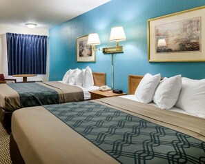 Een hotelkamer met twee bedden, een bureau, een lamp, een telefoon en een schilderij aan de muur.