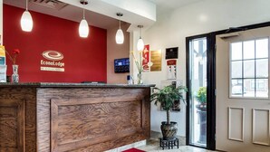 A reception desk with a red wall, a wooden reception area, and a doormat with the hotel logo. - Econo Lodge Lawrence near University (Lawrence)