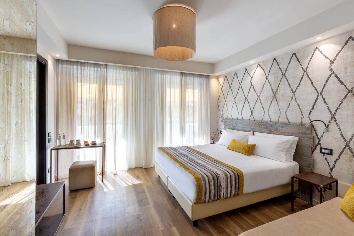 A modern hotel room with a large bed, a desk, and a seating area.
