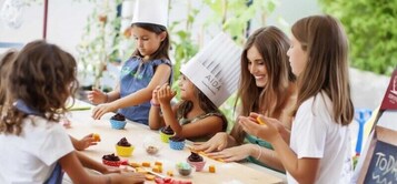 Un grupo de personas participa en una actividad de cocina, con cupcakes e ingredientes sobre la mesa.