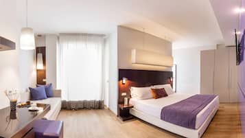 Ein modernes Hotelzimmer mit einem Bett, einer Sitzecke, einem Schreibtisch und einem an der Wand befestigten Fernseher.