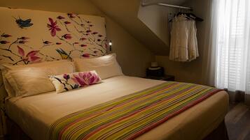 Ein Schlafzimmer mit einem großen Bett, einem blumigen Kopfende und einem Fenster mit Vorhängen.