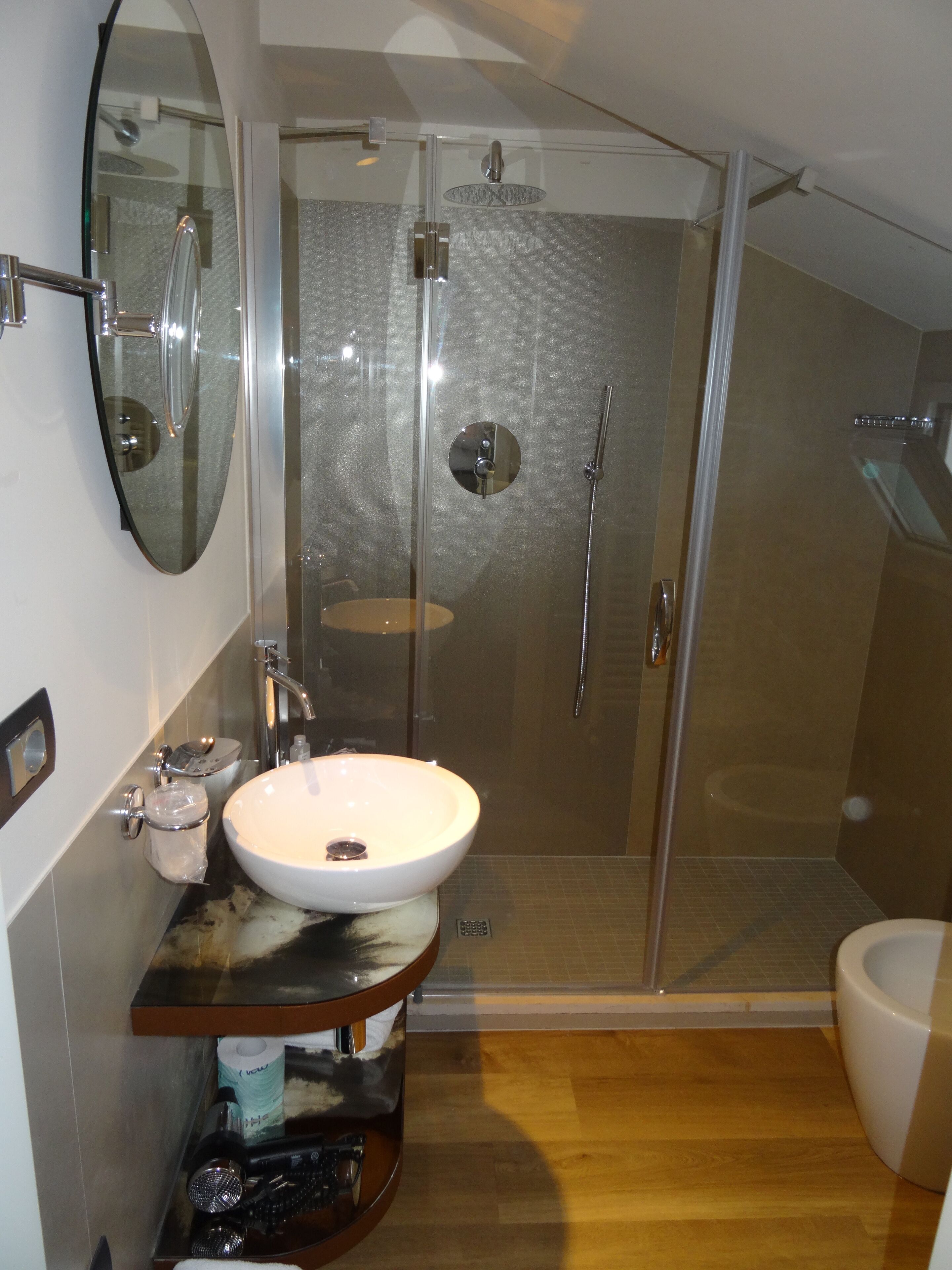 A modern bathroom with a glass-enclosed shower, a white sink, and a wooden vanity.