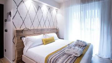 Una cama bien hecha con sábanas blancas, cabecera de madera y una almohada amarilla.