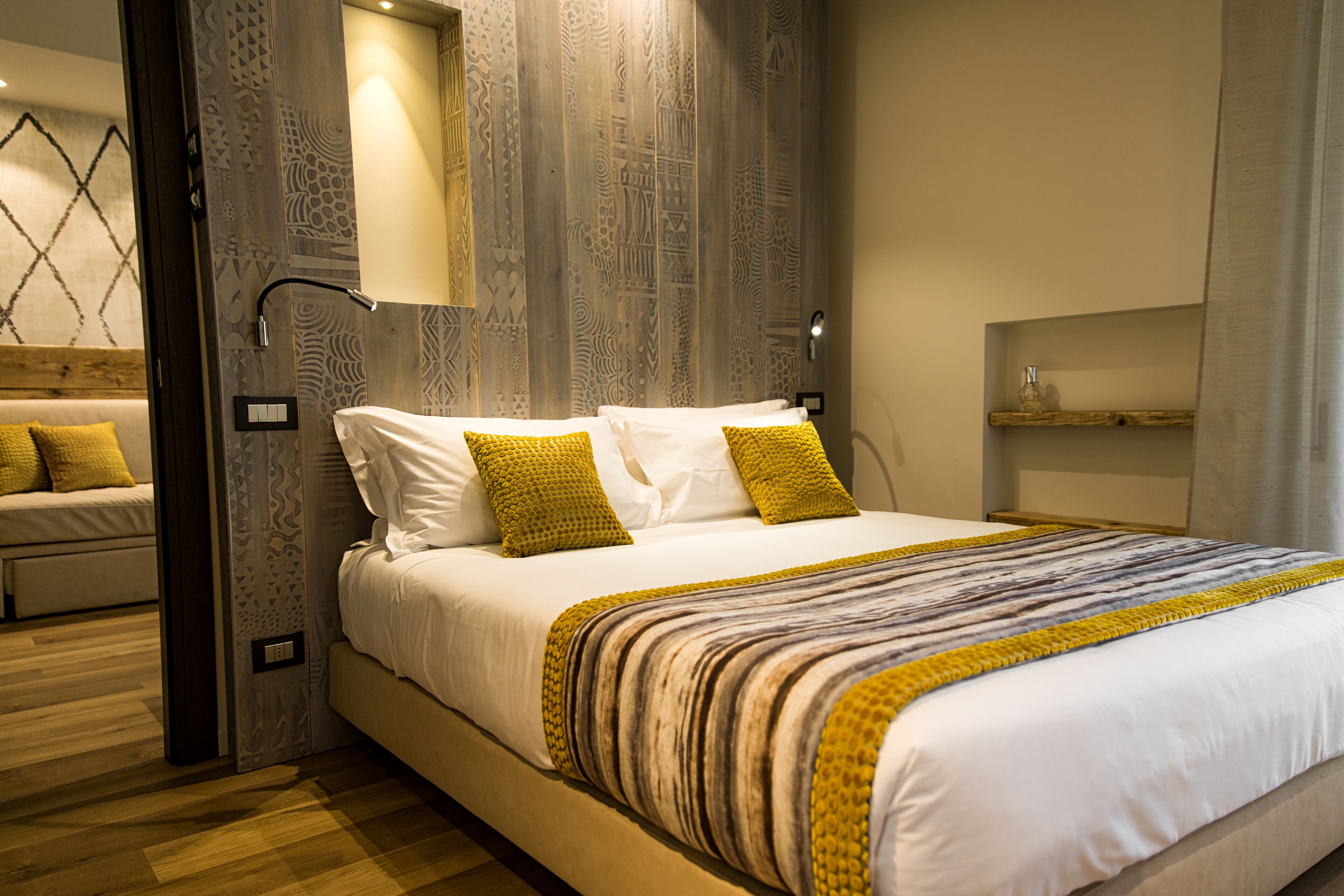 A modern bedroom with a large bed, a bedside table, and a wall-mounted lamp.
