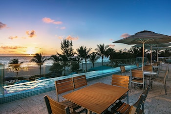 Relax by the infinity pool overlooking the ocean and palm trees. at Marenas Beach Resort