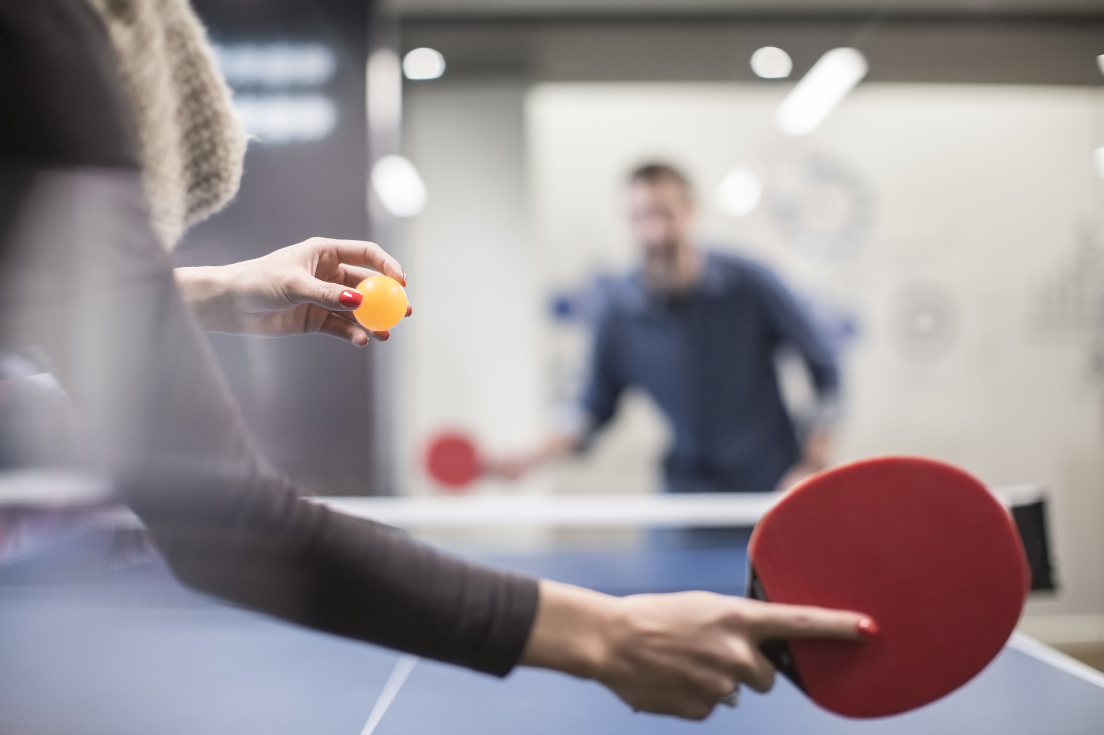 Una mesa de ping pong con un jugador sosteniendo una paleta y una pelota.