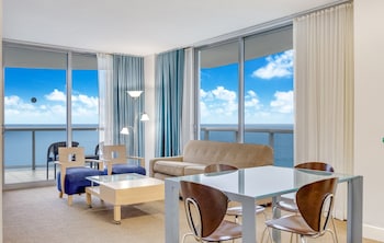 Enjoy breathtaking ocean views from this spacious room featuring a glass dining table, comfortable seating area, and large windows. at Marenas Beach Resort