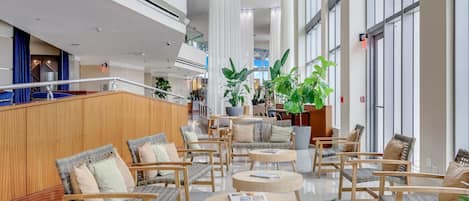 Un vestíbulo espacioso con techos altos, muebles de mimbre modernos y amplias ventanas.