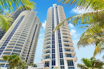 Two high-rise buildings with balconies and large windows, set amidst lush palm trees. at Marenas Beach Resort