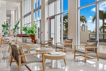 Relax in a spacious lobby with large windows offering views of palm trees and the city. at Marenas Beach Resort