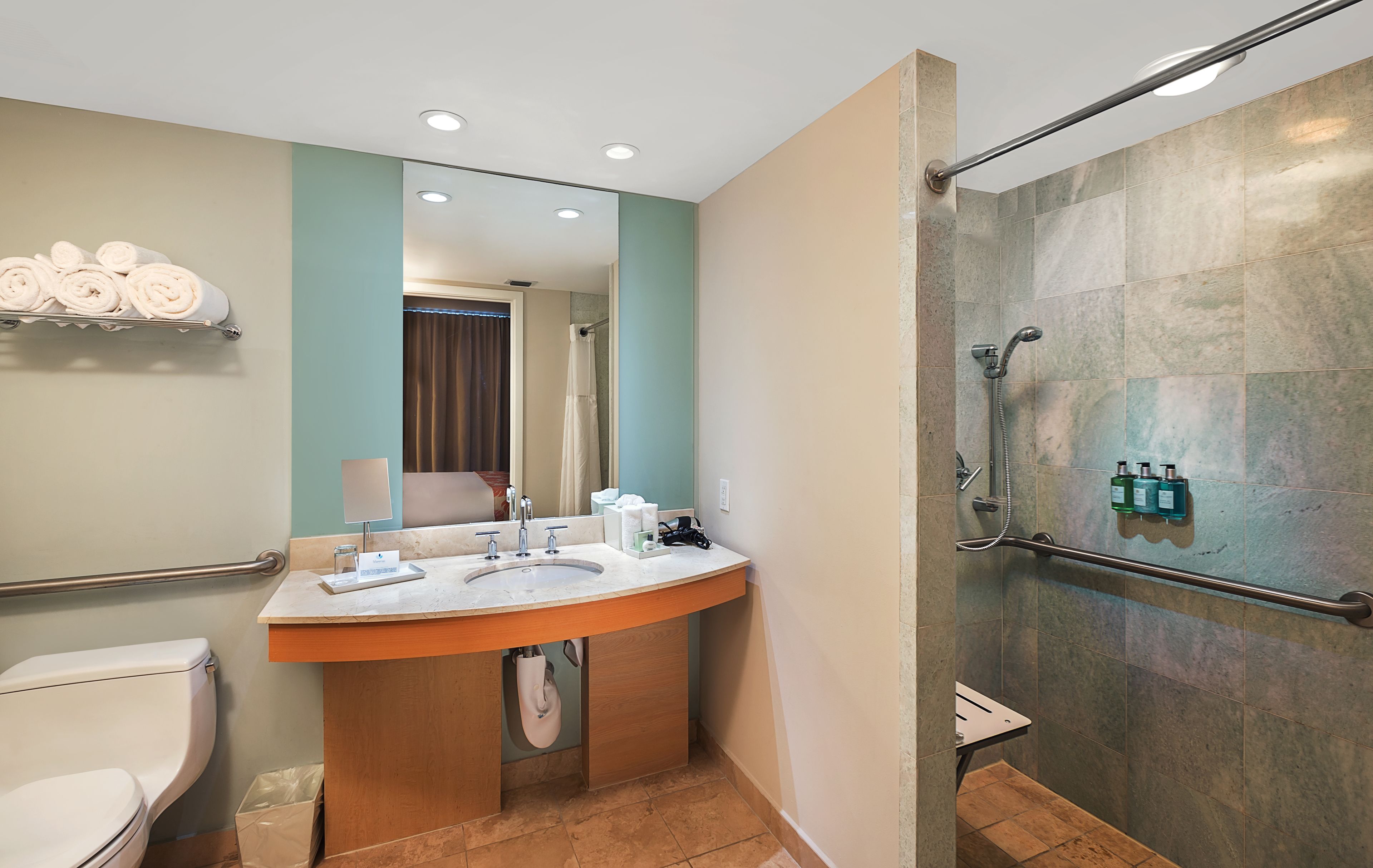 Un baño moderno con lavamanos, espejo y ducha.