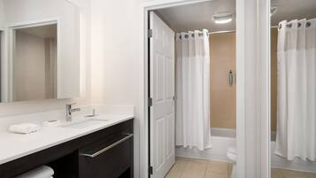 A modern bathroom with a white sink, dark vanity, and a shower curtain.
