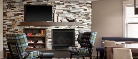 A living room with a fireplace, a flat-screen TV, and a bookshelf.