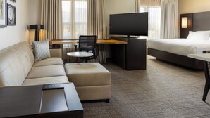 A hotel room with a sofa, a desk, a television, a bed, and a window with curtains. - Residence Inn by Marriott Corona Riverside (Corona)