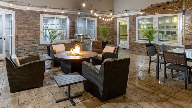An outdoor patio area with a fire pit, wicker furniture, and stone walls. - Residence Inn by Marriott Corona Riverside (Corona)