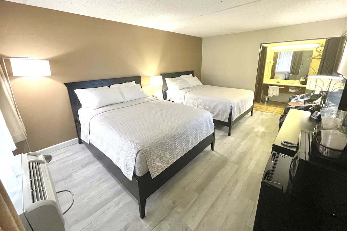 Habitación de hotel con dos camas, un escritorio, un espejo y un radiador.