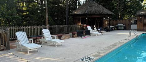 Un área de piscina con sillones de descanso y una zona de barbacoa.