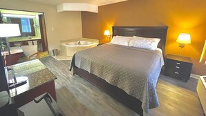 Une chambre d’hôtel avec un grand lit, un bureau avec une chaise, une coiffeuse avec un miroir et une baignoire.