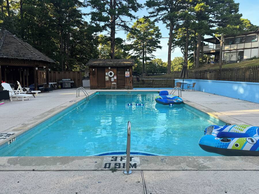 A swimming pool with lounge chairs, a small wooden hut, and a lifeguard stand.