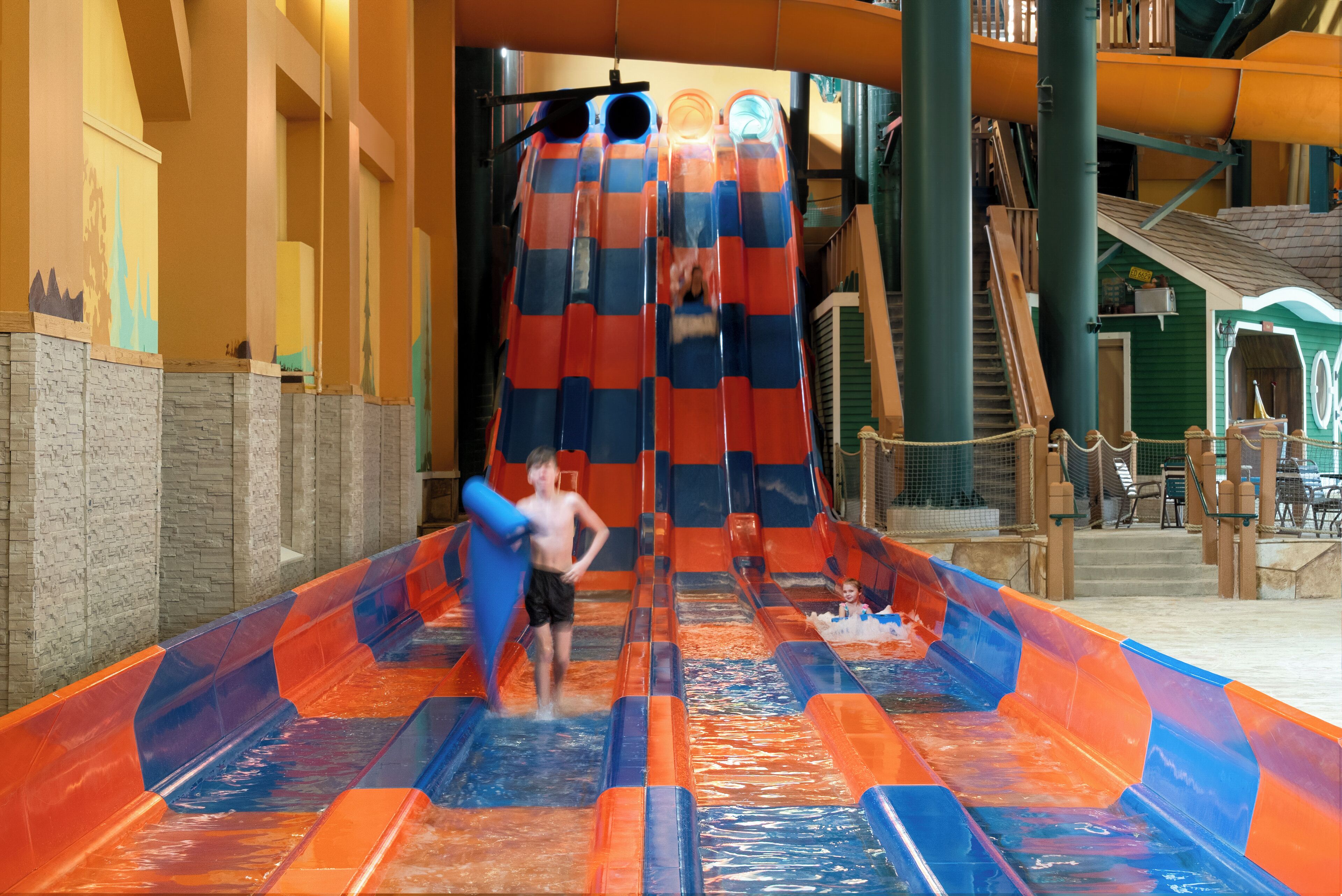 Un toboggan aquatique avec plusieurs pistes et un enfant en haut.